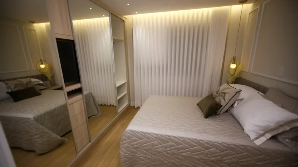 Quarto pequeno minimalista com iluminação fria-LED na sanca ao longo de toda a parede com cortina, luminaria pendente com luz quente ao lado da cama.